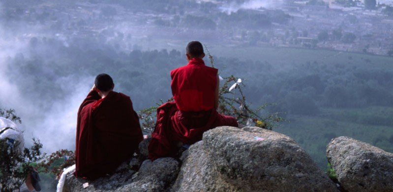 two tibetan monks overlooking a mountain view