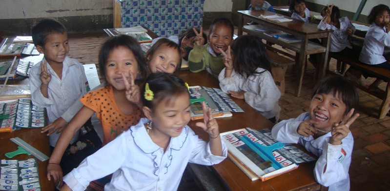 children in a classroom giving a peace sign