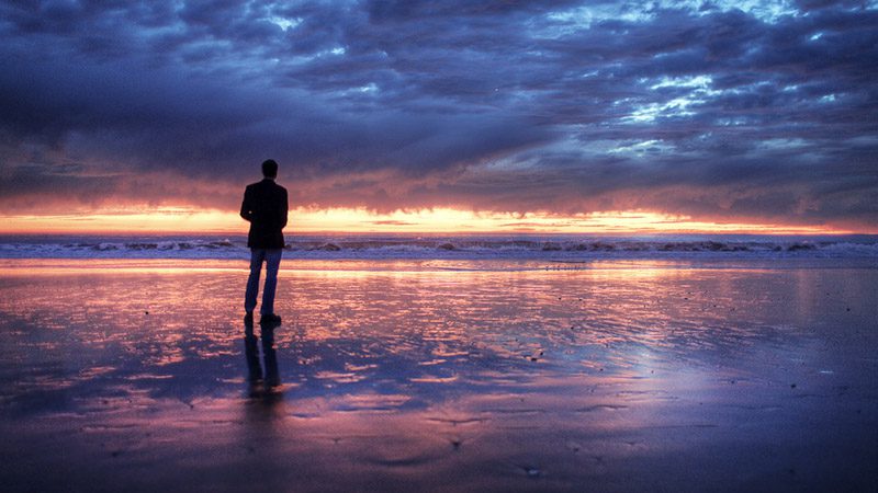 image a man sitting alone on the sea beach
