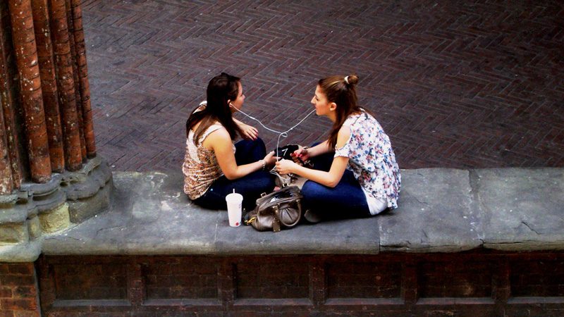 Friends forever means sharing earbuds. Image magellano, Flickr 