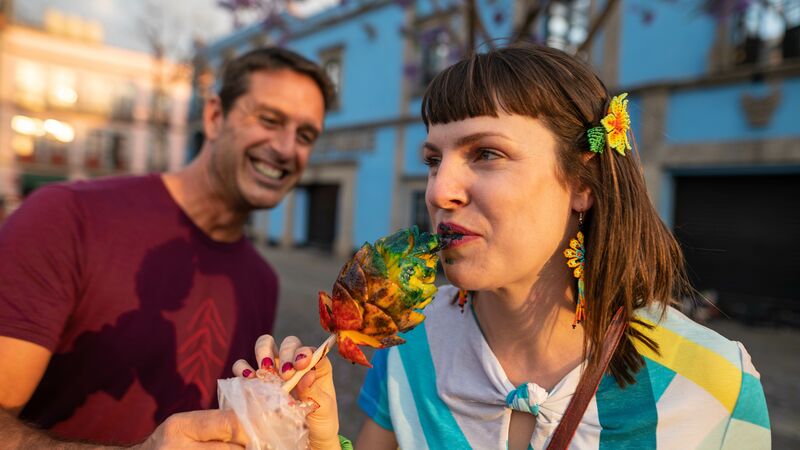 A woman eating a piece of pineapple on a stick