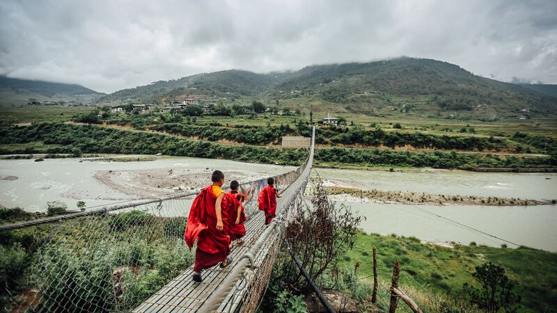 Monks walking across a bridge over a river