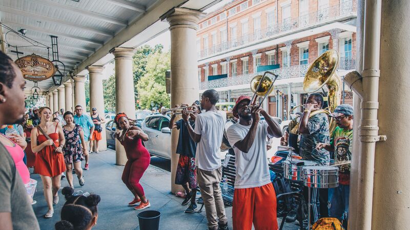 A group of men play trumpets while a woman dances