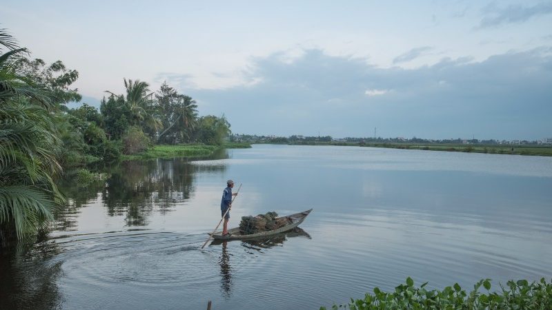 A farmer rows across a lake in Hoi An