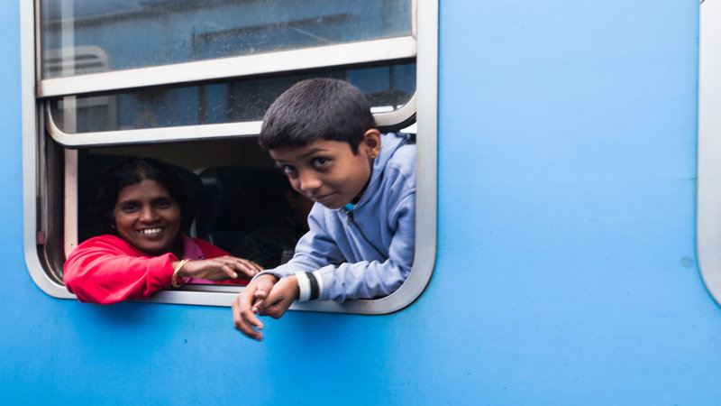 A young boy and his mother peer out of the train window.