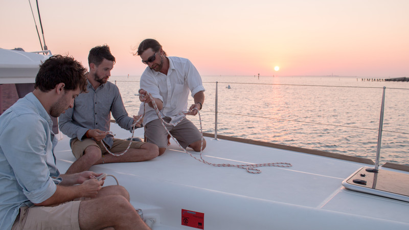 Photo of crew tying knots on catamaran.