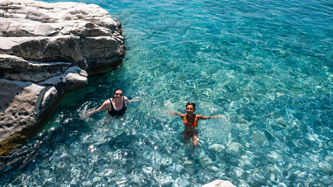 Two travellers swimming in crystal clear water in Crete, Greece