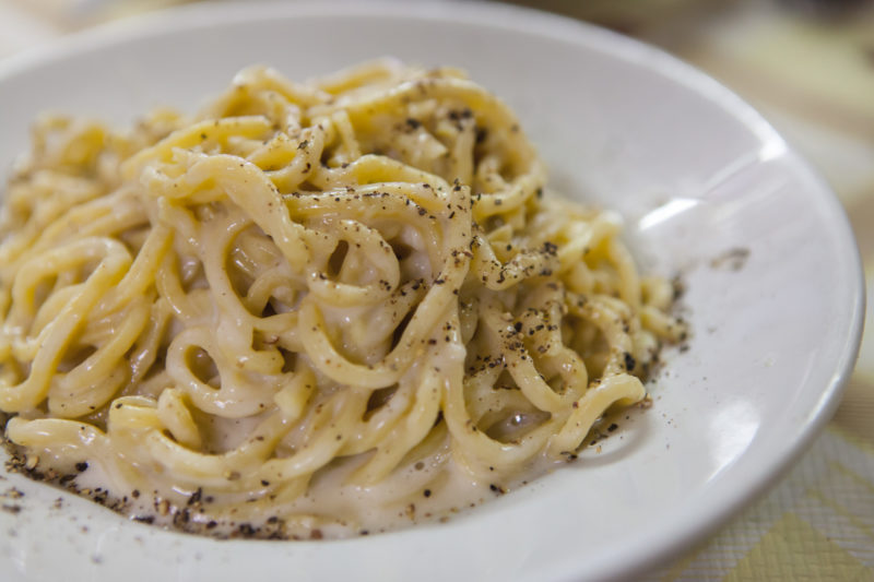 A silky plate of pasta bathed in a cream sauce and dotted with a generous amount of pepper.