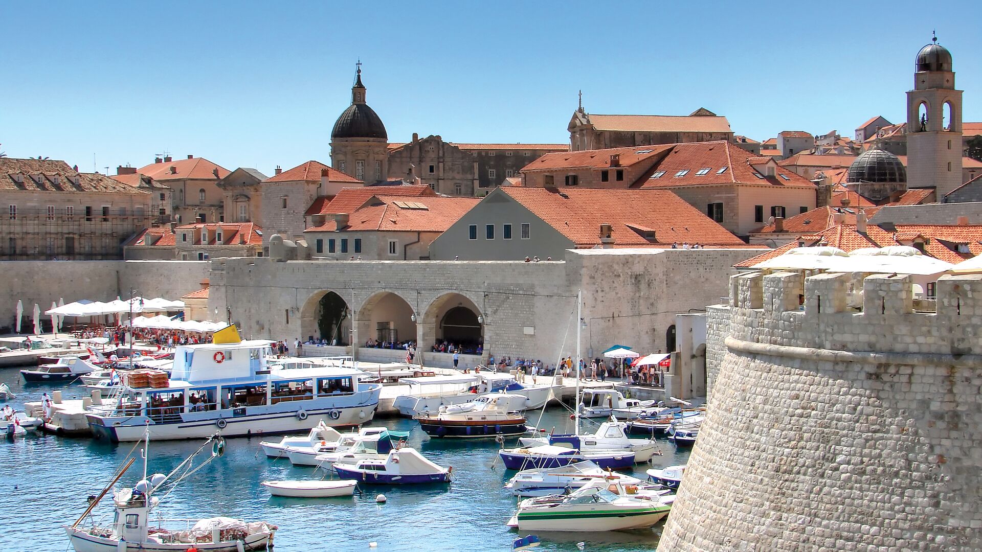 Lots of boats in Dubrovnik's Old Town harbour on water, surrounded by city walls