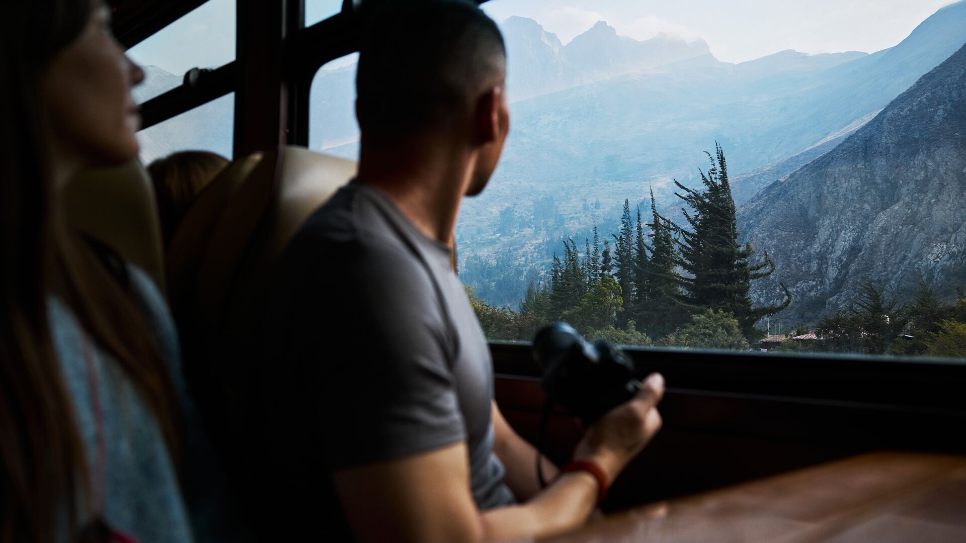 Two travellers admiring the view of the  rugged Andean highlands on the scenic train to Machu Picchu