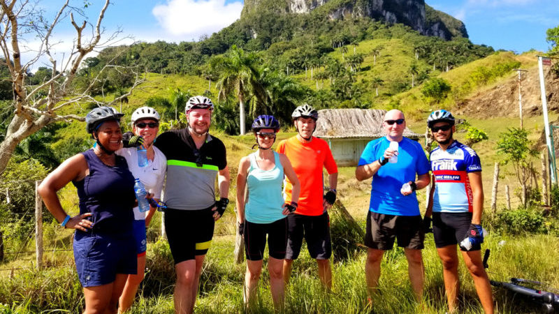 A group of cyclists pose in front of a karst mountain