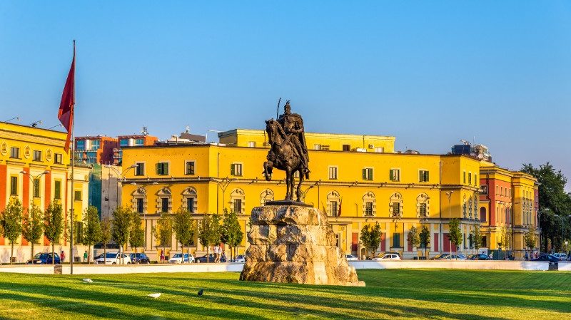 Statue and Albanian flag in Tirana