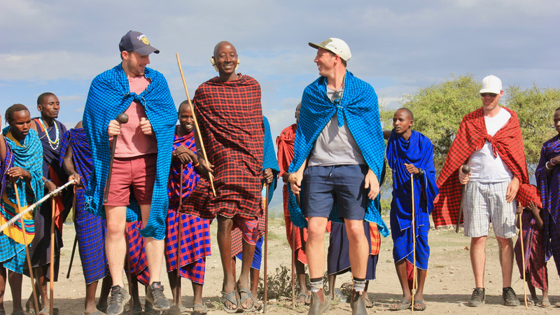 Two men perform a jumping dance with a Maasai warrior