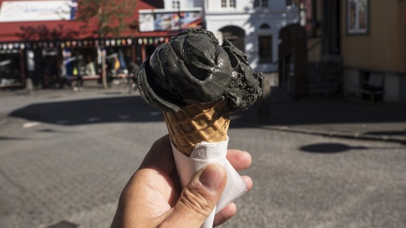 A hand holds onto a liquorice-flavoured ice cream cone