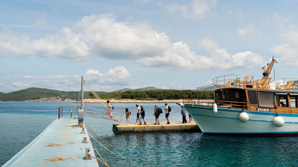 Travellers disembark a boat and walk to a pier in Croatia