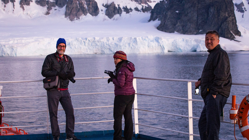 Three travellers on deck in Antarctica