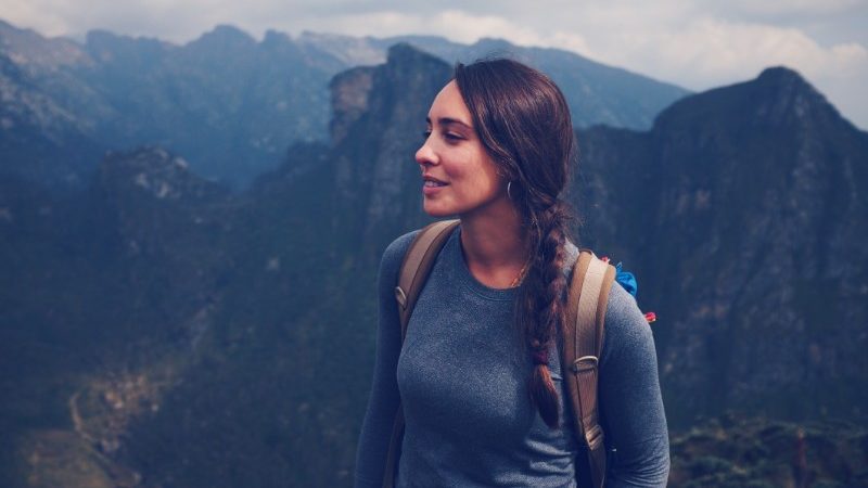 A young woman stands on a mountain