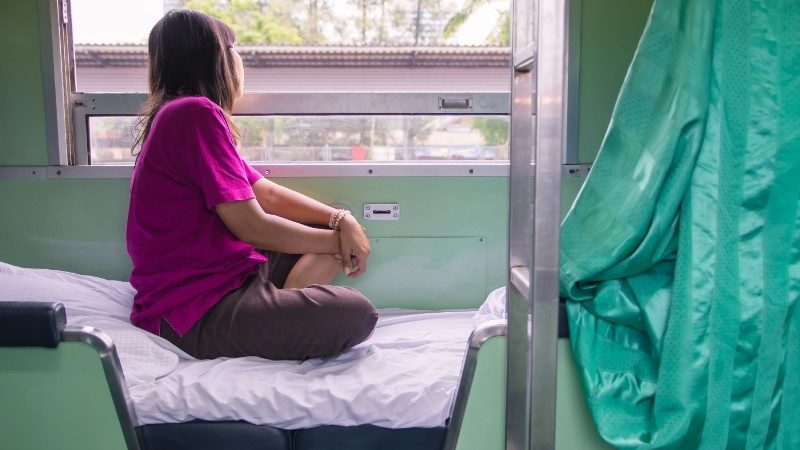 A traveller gazing out of the window on an overnight train in Thailand