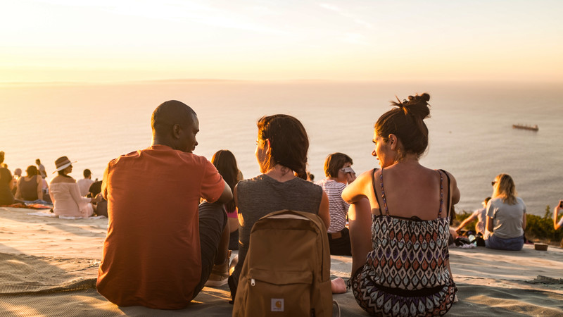 Three travellers watch the sunset in Cape Town