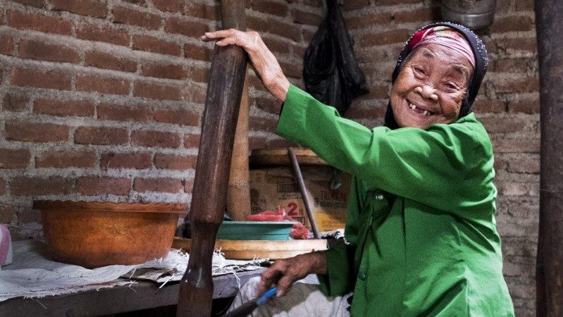 An old woman grinding coffee beans