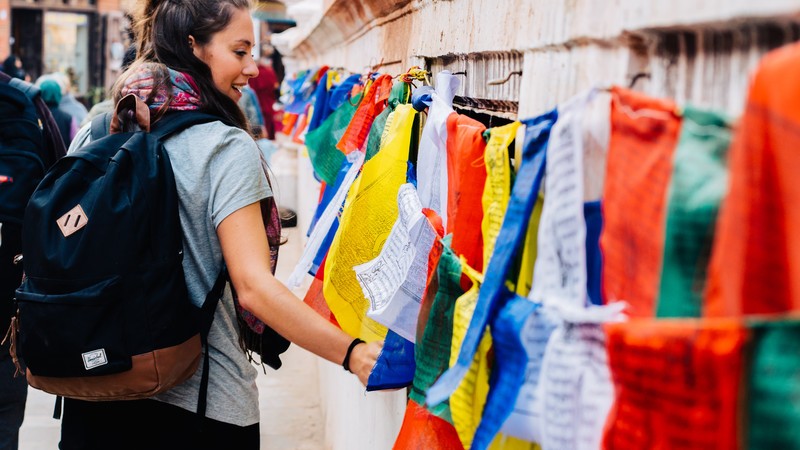 A young woman walks past a row of prayer flags