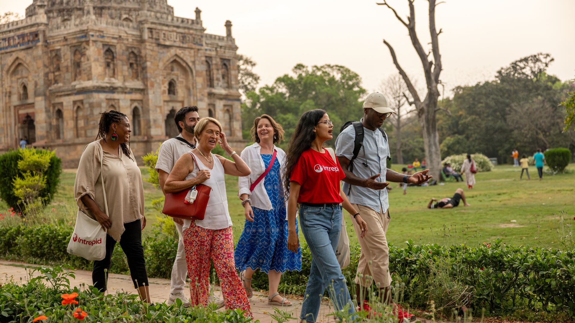 A group of five travellers and a local Intrepid leader walking on a path in Lodhi Garden in New Delhi, India.