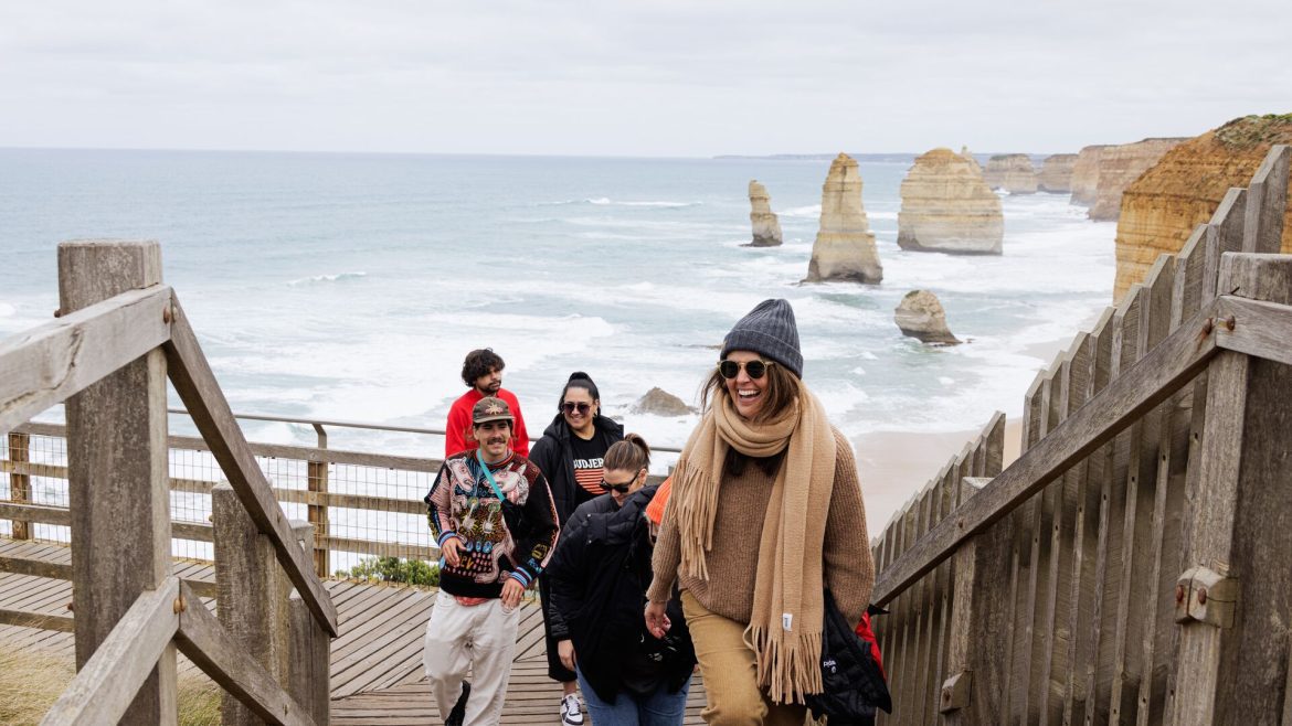 A group of people climb up stairs of a lookout to the Twelve Apostles