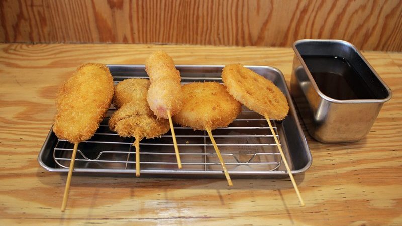 Skewers of crumbed vegetables on a hot plate