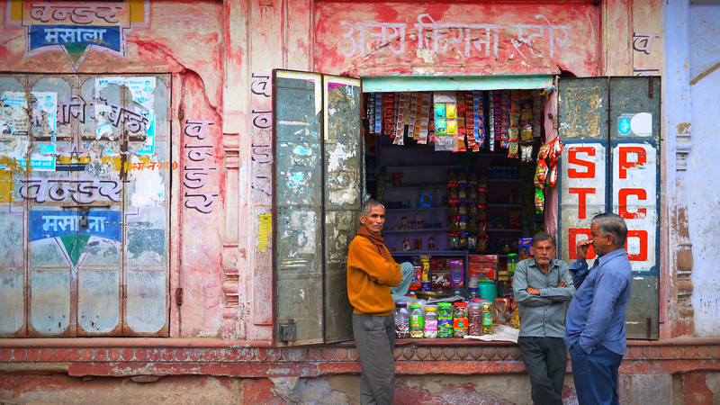 Three men standing outside a shop