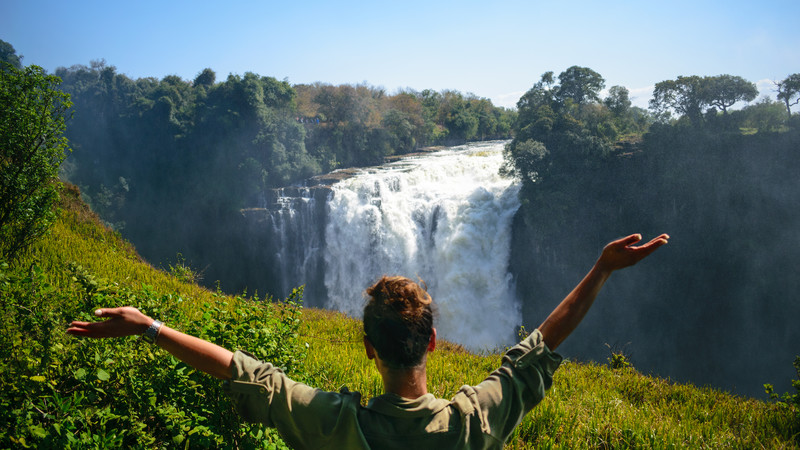 Girl with arms up looking at Victoria Falls