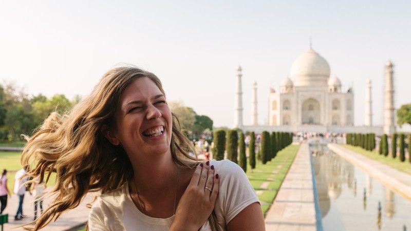 smiling female traveller in front of Taj Mahal