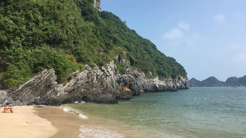 A woman sits on the beach on Cat Ba Island