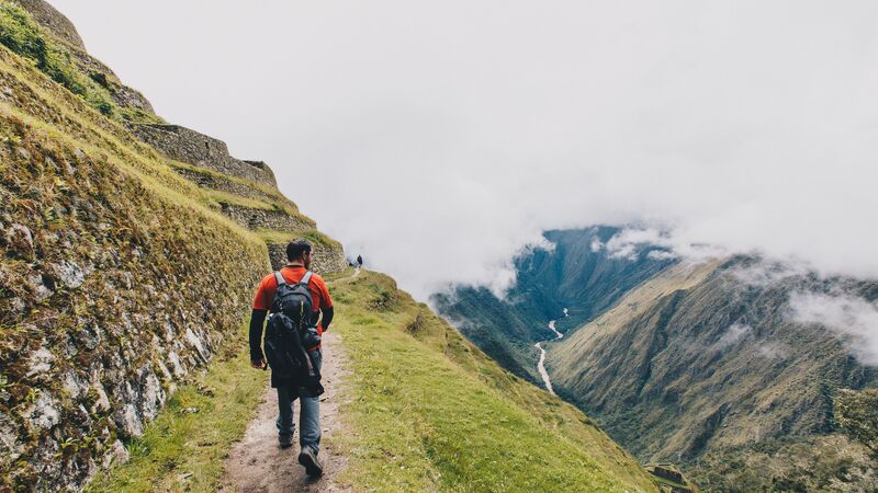 A male trekker wearing a backpack on the Inca Trail