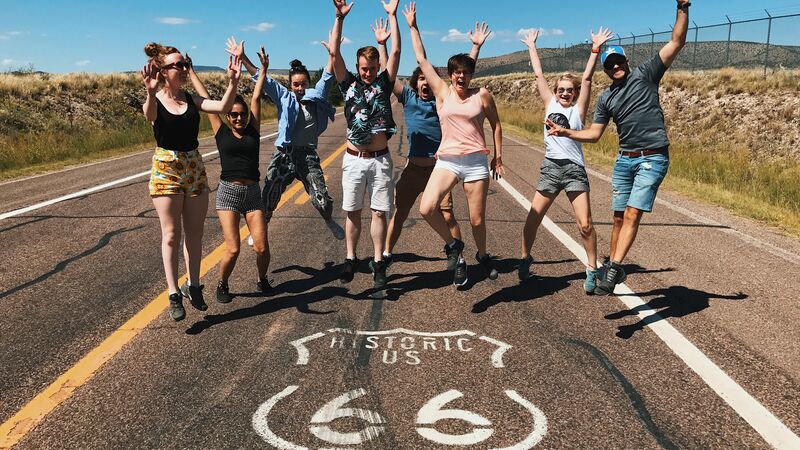 A group of travellers jumping in the middle of the road on Route 66.