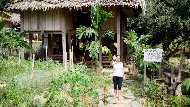 A woman waves outside her homestay in Da Bac