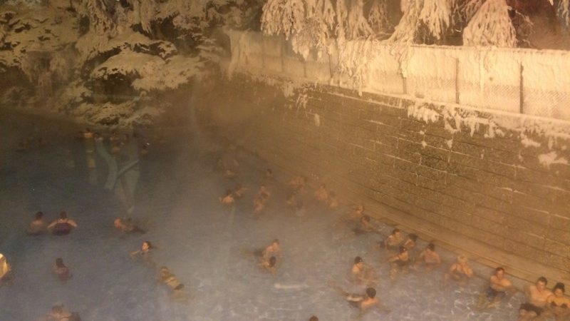 People sitting in a hot spring in the snow in Canada