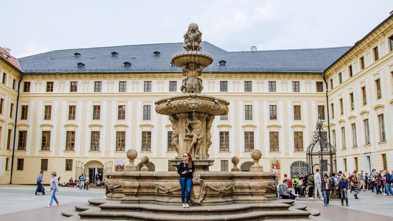 A woman standing at a fountain in the Prague Castle 