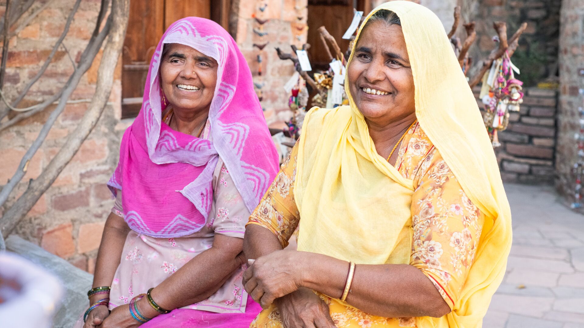 Two local women smiling in India in colourful traditional clothing.