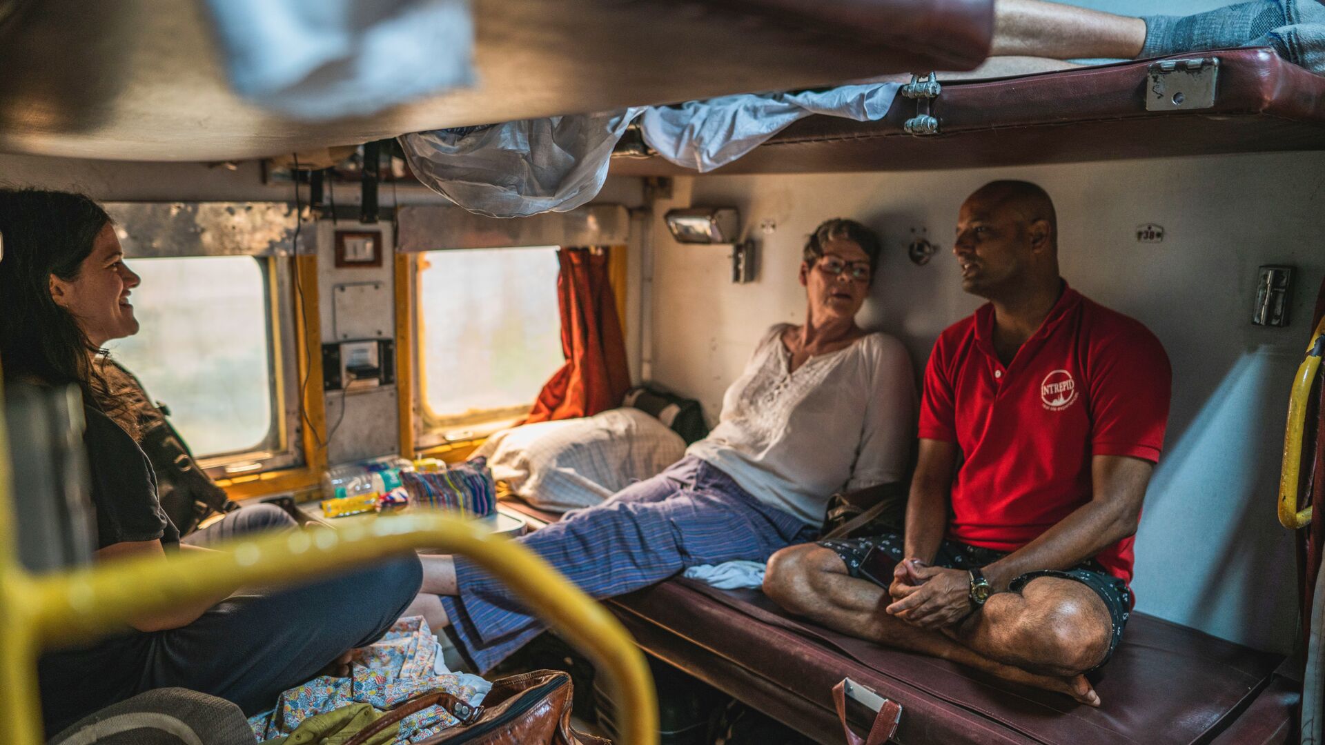 Two travellers and an Intrepid local leader on an overnight train in India.