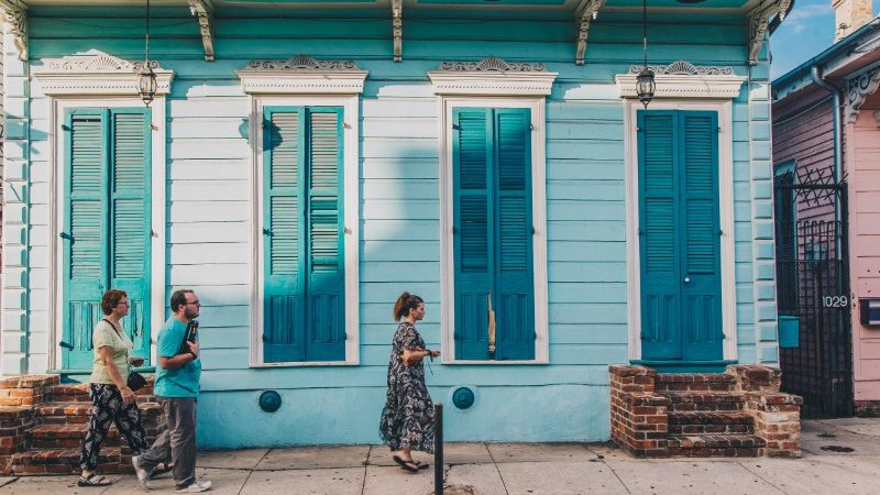 Travellers walking past a blue building