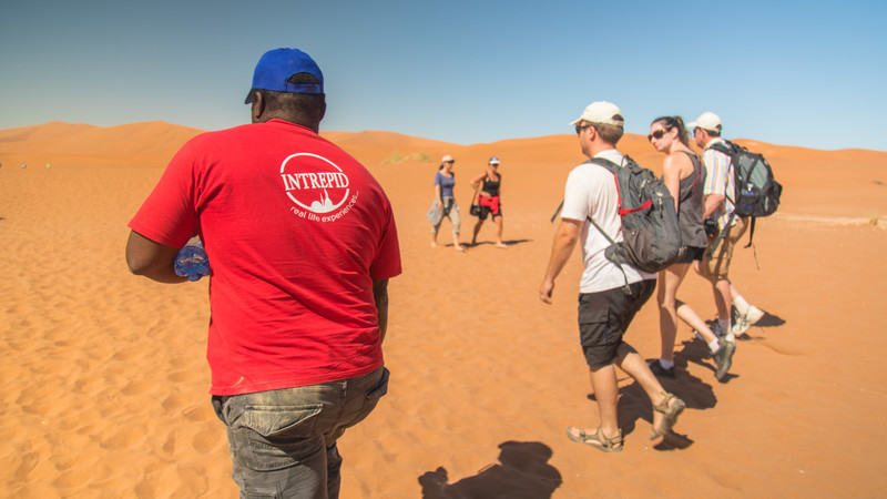 An Intrepid leader and travellers on a sand dune