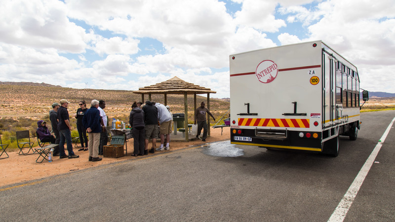 Travellers having lunch next to an overland truck