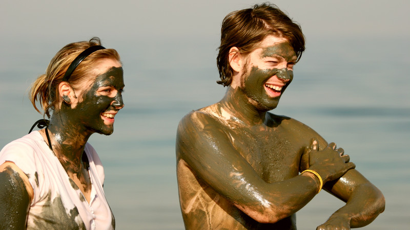 Two travellers covered in mud at the Dead Sea