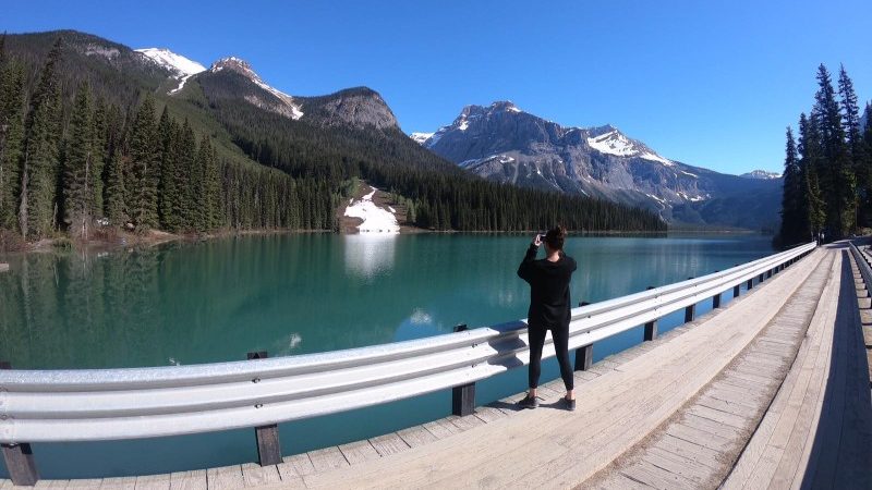 A woman takes a photo in the Rocky Mountains, Canada