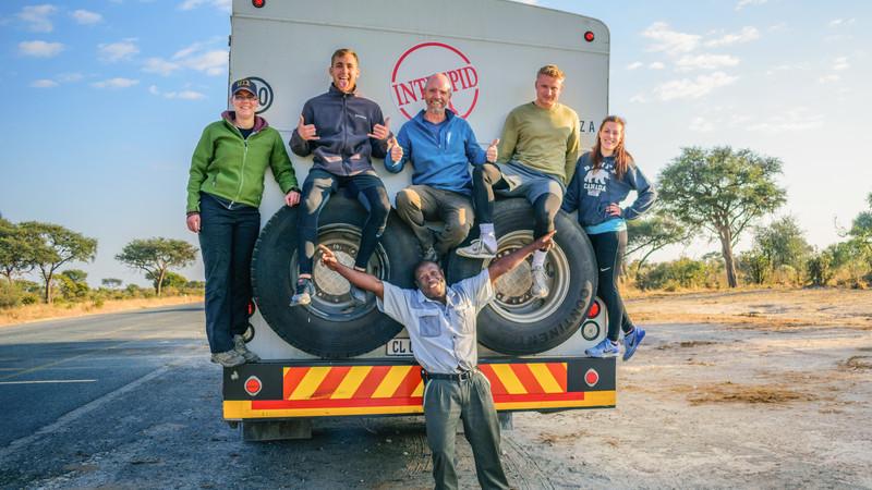 A group of people sitting on the tyres of a truck