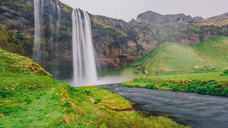 On of Iceland's spectacular waterfalls stands out against a vibrant green background.