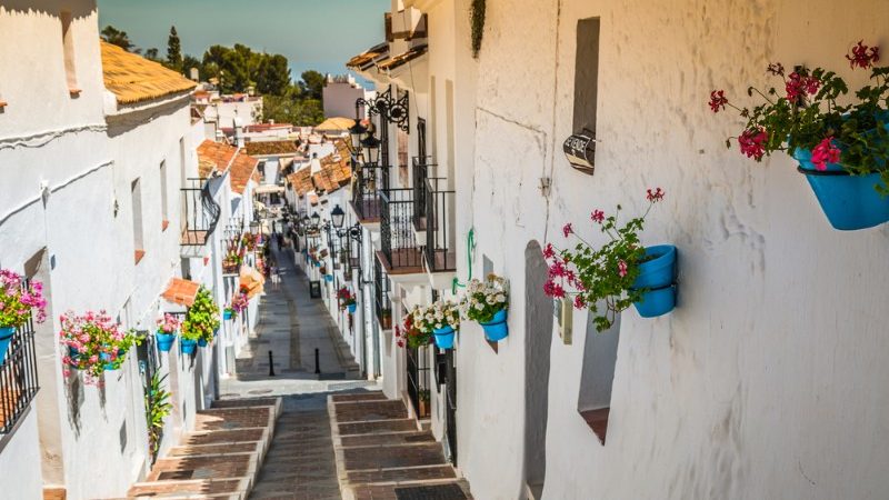 Colourful flowerpots hanging on white walled buildings in Mijas Pueblo, Spain