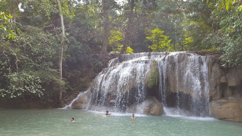 People swimming under a waterfall