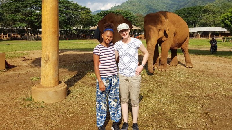 A mother and daughter in front of two elephants