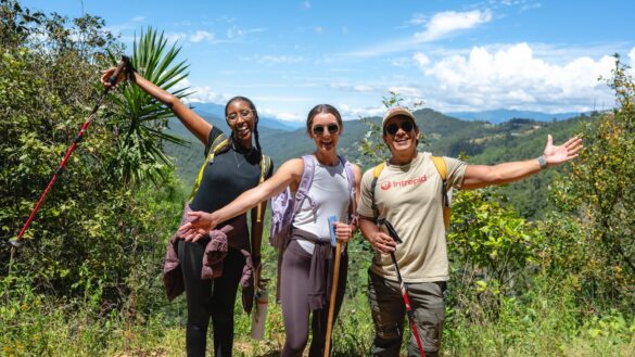 Two travellers and an Intrepid local leader posing with their arms up on a hike in the mountains of Mexico.